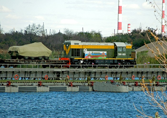 Đoàn tàu chở xe quân sự chạy trên cầu phao bắc qua sông